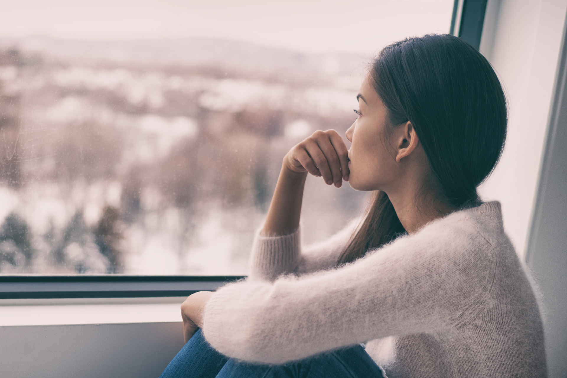 Woman looking out the window with seasonal depression