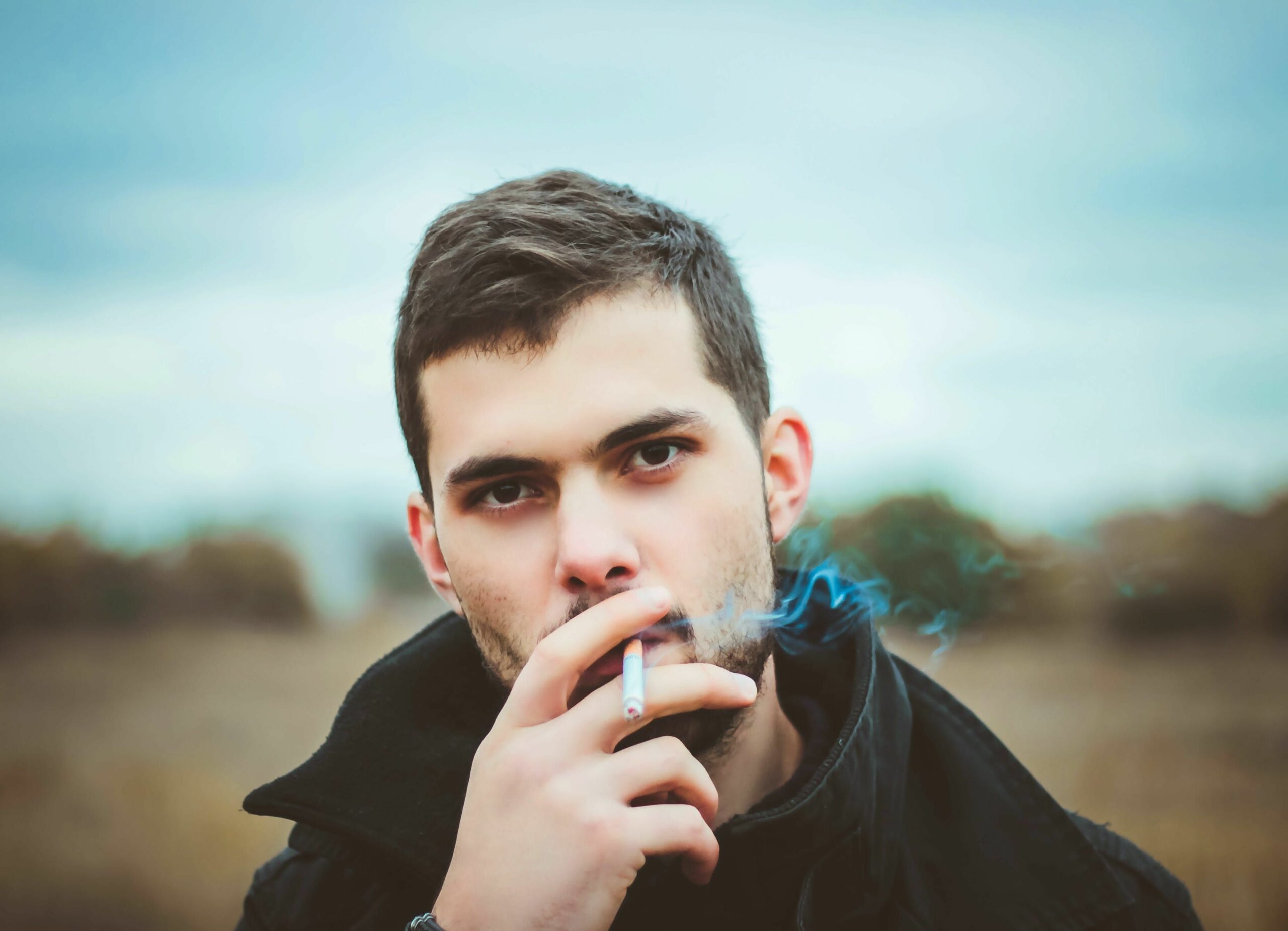 Person looking at the camera with cigarette, to illustrate how cannabis may be able to help you quit smoking