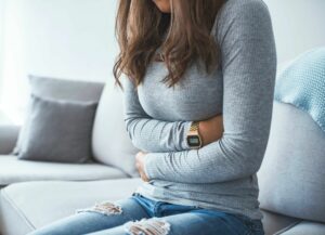 Women clutching her torso in pain to illustrate how using CBD for diarrhea may help