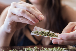 Woman rolls joint to illustrate high-THC vs. low-THC debate